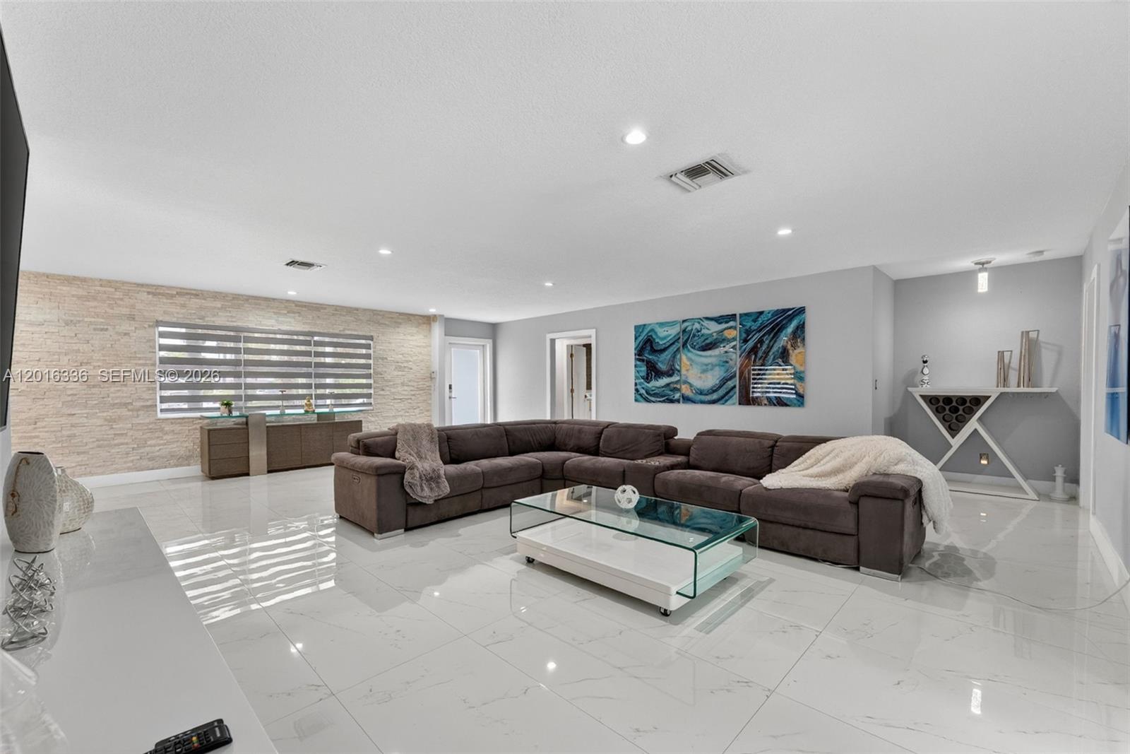 A living room features a large sectional sofa, a glass coffee table, and stone-accented walls — 2918 Cleveland St, Hollywood FL 33020, HOLLYWOOD, FL