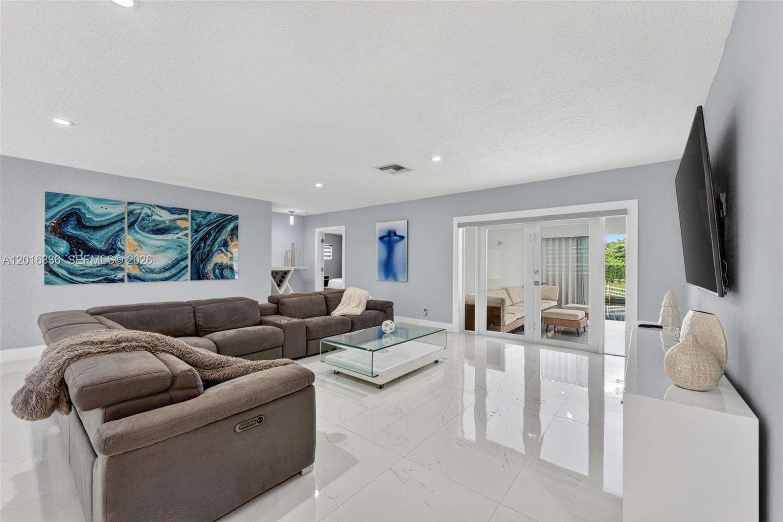 A living room features a large gray sectional sofa, glass coffee table, and white tile floors — 2918 Cleveland St, Hollywood FL 33020, HOLLYWOOD, FL