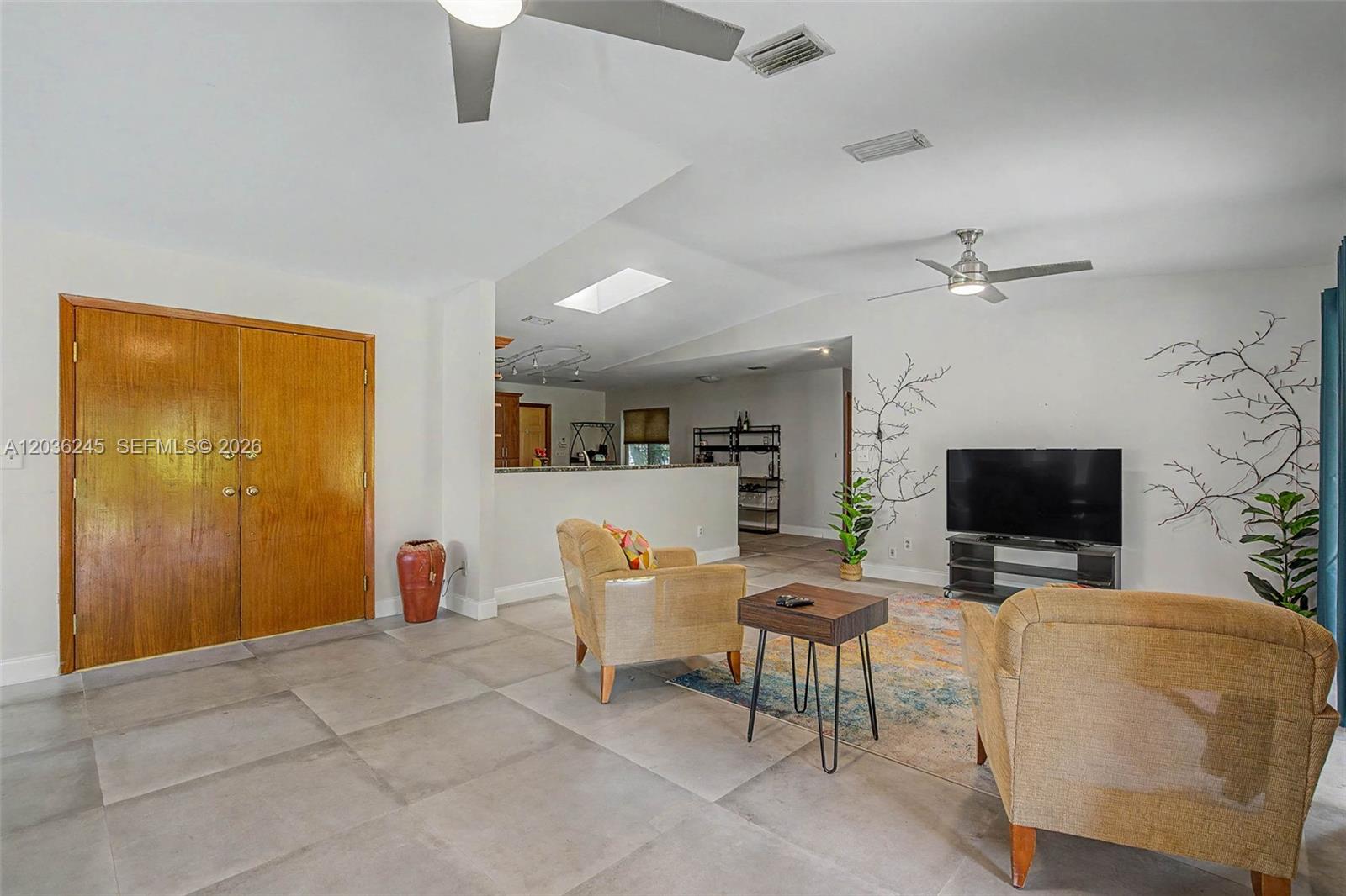 A living room features large gray floor tiles, two tan armchairs, and a television console — 15741 SW 147th Ct, Miami FL 33187, MIAMI, FL