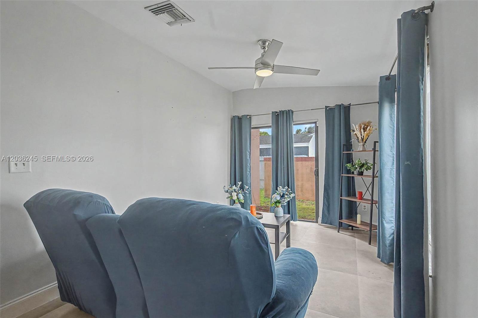 A living room features a blue sofa, a ceiling fan, and sliding glass doors — 15741 SW 147th Ct, Miami FL 33187, MIAMI, FL