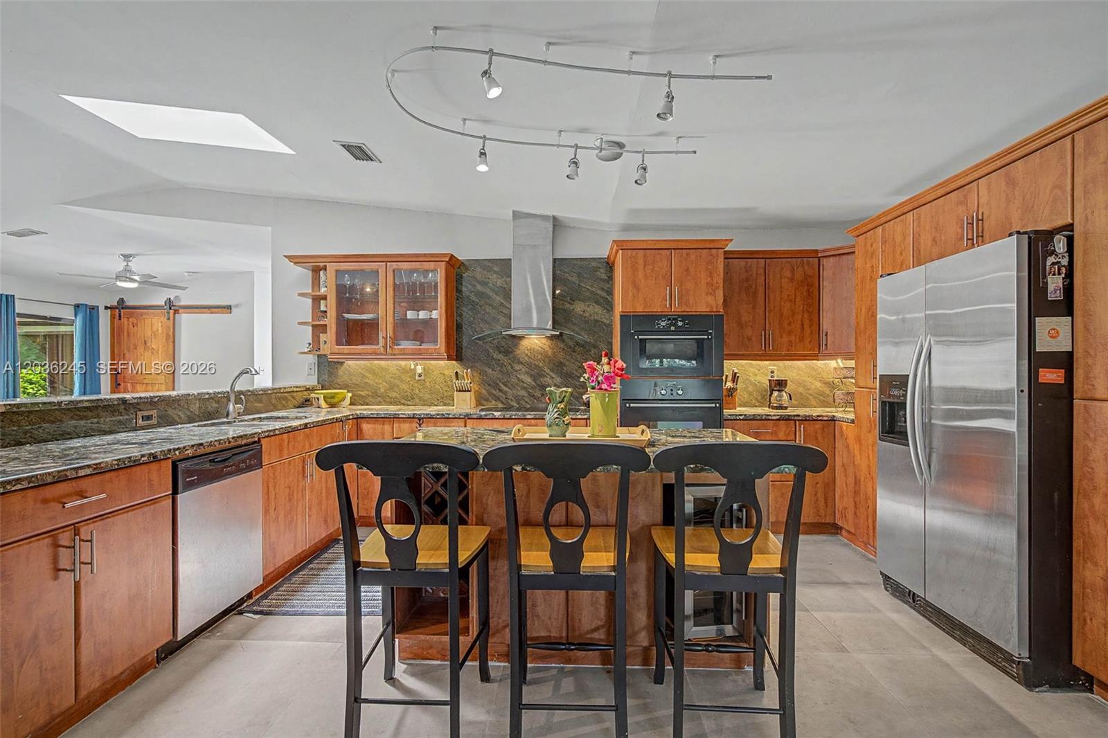 A kitchen features wood cabinets, granite countertops, stainless steel appliances, and a central island — 15741 SW 147th Ct, Miami FL 33187, MIAMI, FL