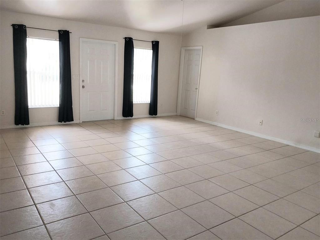 An empty room features light-colored floor tiles, white walls, and two windows with black curtains — 1695 GAUGUIN ROAD, NORTH PORT, FL