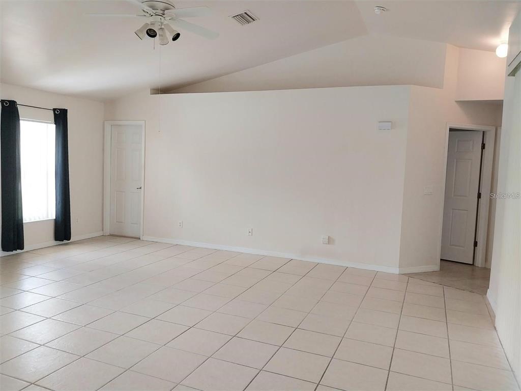 A spacious room with white tiled floors, a vaulted ceiling, and two closed doors — 1695 GAUGUIN ROAD, NORTH PORT, FL