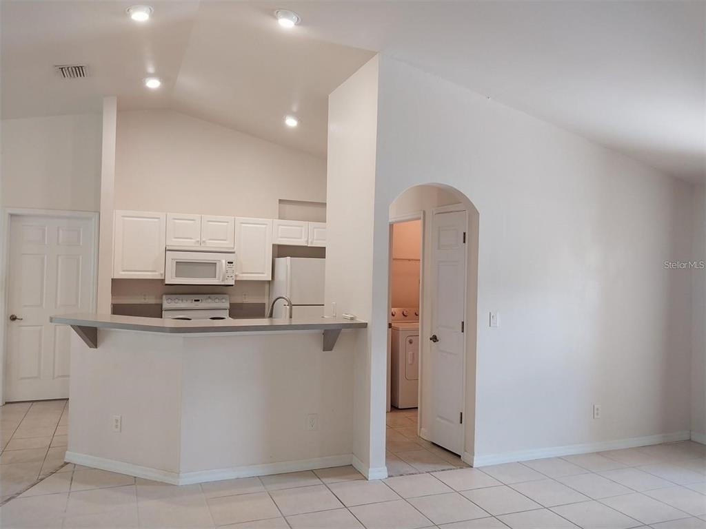 A kitchen with white cabinets and a breakfast bar opens to a laundry room area — 1695 GAUGUIN ROAD, NORTH PORT, FL