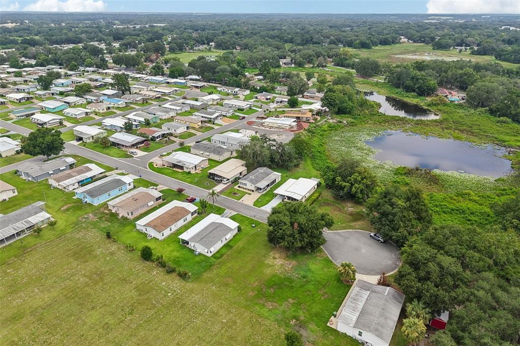 An aerial view shows a residential neighborhood of mobile homes adjacent to a large pond — 2341 W COACH N FOUR DRIVE, LEESBURG, FL