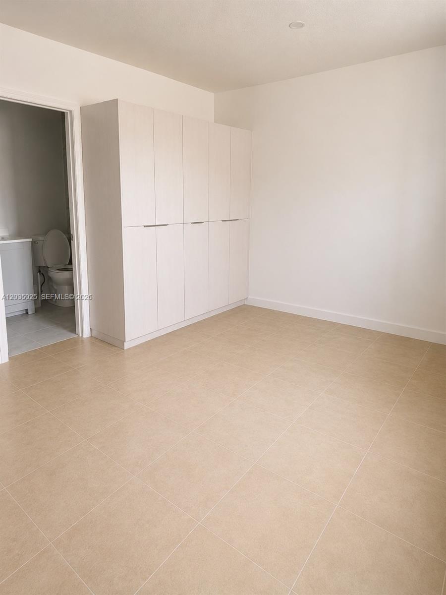 A room with light-colored tile flooring features a large, built-in white storage cabinet — 11931 SW 132nd Ave, Miami FL 33186, MIAMI, FL