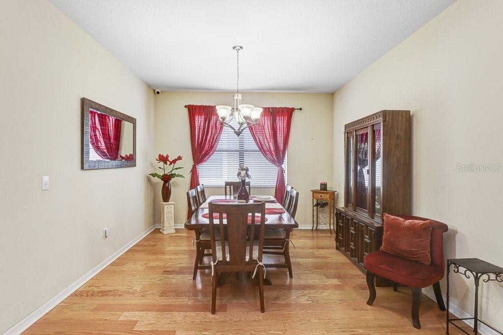 A dining room features hardwood floors, a wooden table with six chairs, and red curtains — 13931 FELIX WILL ROAD, RIVERVIEW, FL