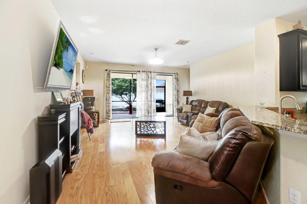 A living room features hardwood floors, a brown leather sofa, and a sliding glass door — 13931 FELIX WILL ROAD, RIVERVIEW, FL