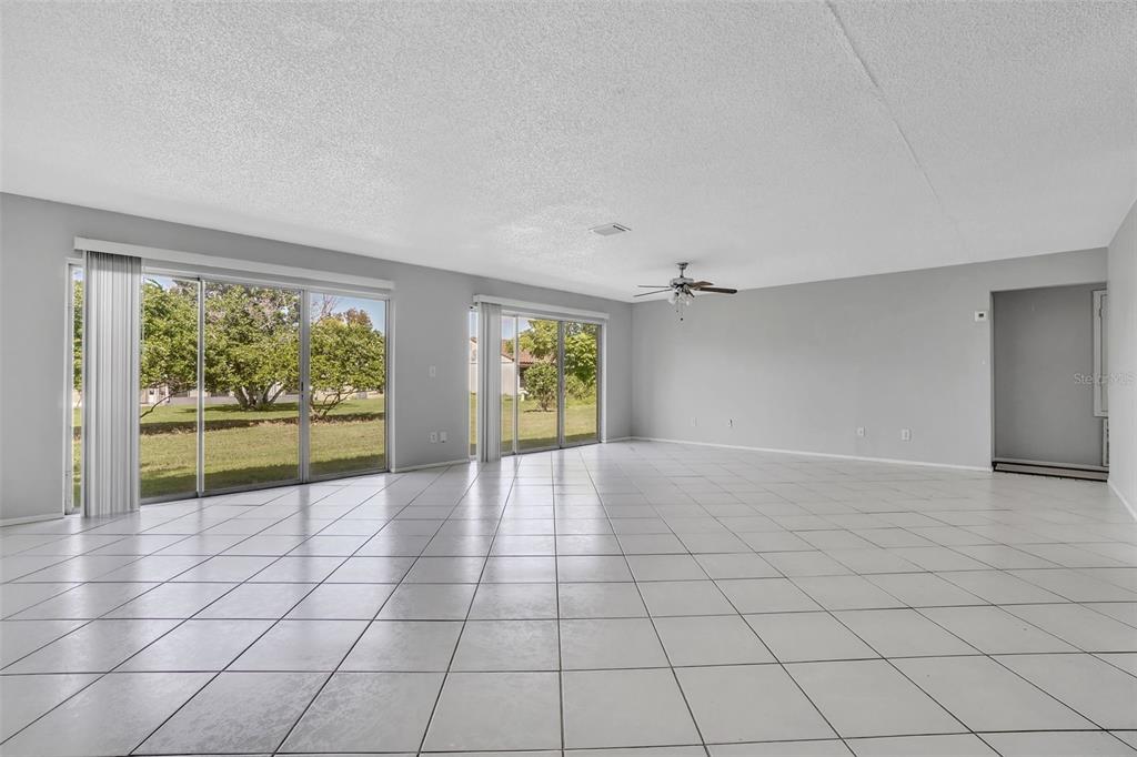 An empty living room features white tile flooring, light gray walls, and two sliding glass doors — 10626 DEERGRASS LANE, ORLANDO, FL