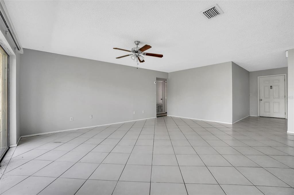 An empty room with light gray walls, white tile flooring, and a ceiling fan — 10626 DEERGRASS LANE, ORLANDO, FL