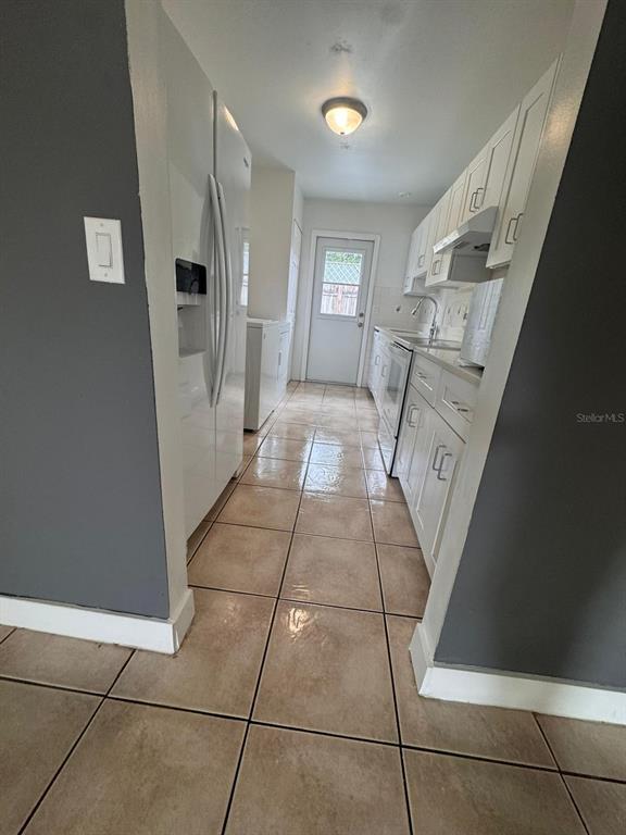 A narrow kitchen features white cabinets, stainless steel appliances, and light-colored tile flooring — 725 NORTHLAKE BOULEVARD UNIT 38, ALTAMONTE SPRINGS, FL