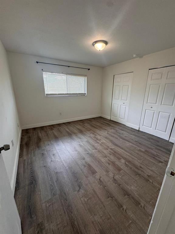 An empty bedroom features white walls, wood-look flooring, a window with blinds, and two closets — 725 NORTHLAKE BOULEVARD UNIT 38, ALTAMONTE SPRINGS, FL