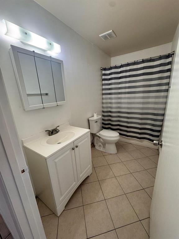 A bathroom features a white vanity, a medicine cabinet, a toilet, and a striped shower curtain — 725 NORTHLAKE BOULEVARD UNIT 38, ALTAMONTE SPRINGS, FL