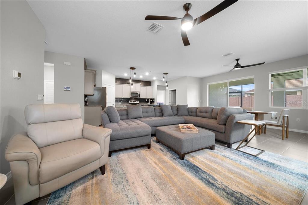 A living room with a gray sectional sofa, a beige armchair, and an open kitchen — 5556 NW 41ST LANE, OCALA, FL