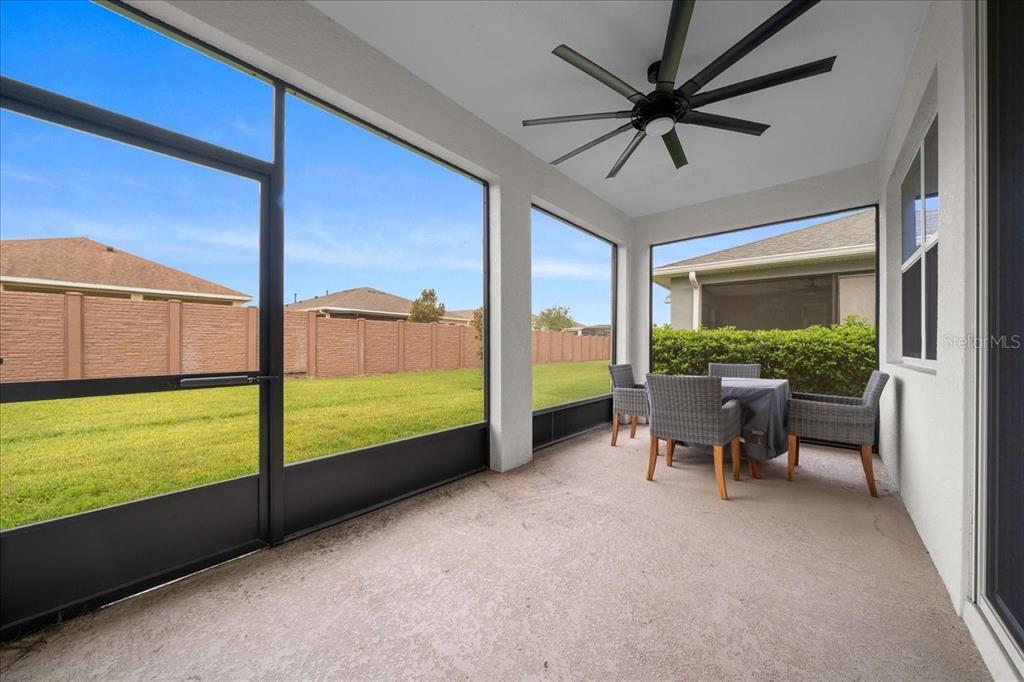 A screened-in patio features a ceiling fan, concrete flooring, and a view of the backyard — 5556 NW 41ST LANE, OCALA, FL