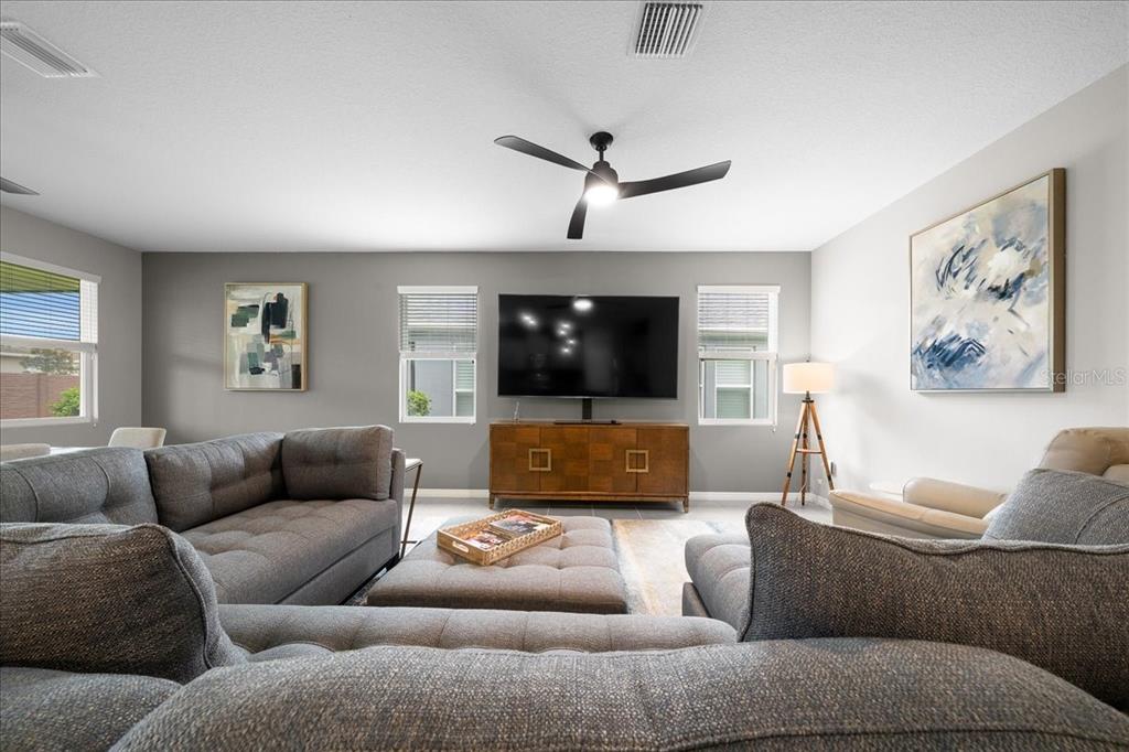 A living room features a gray sectional sofa, a television on a wooden console, and artwork — 5556 NW 41ST LANE, OCALA, FL
