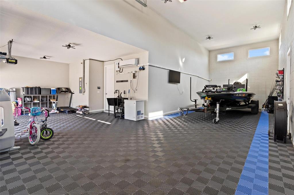 A spacious garage features checkered flooring, a boat on a trailer, and a utility sink — 31788 BROADWATER AVENUE, LEESBURG, FL