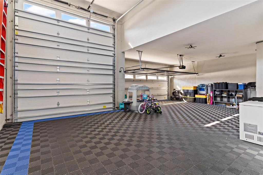 A spacious garage features a high ceiling, a checkered floor, and two large overhead doors — 31788 BROADWATER AVENUE, LEESBURG, FL