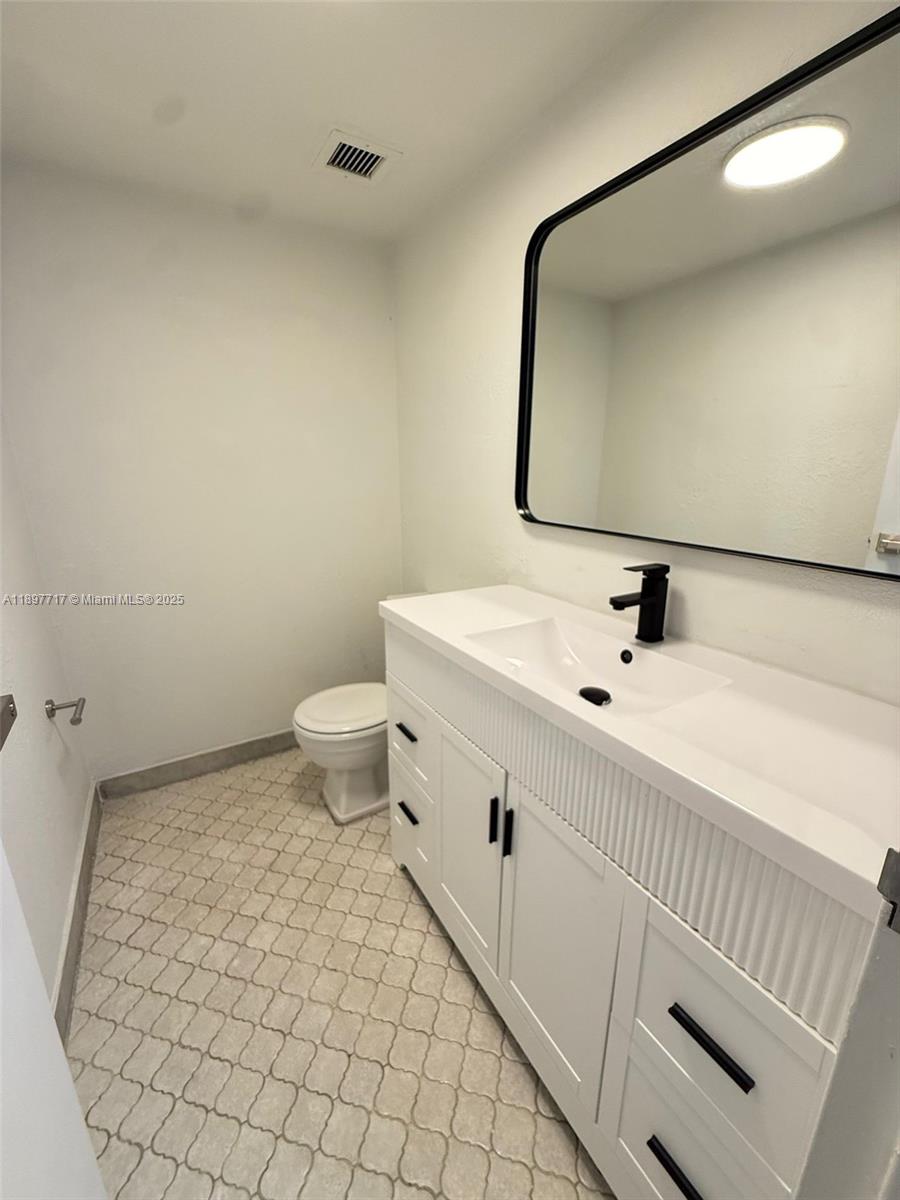 A bathroom features a white vanity with a black faucet, a mirror, and patterned flooring — 13499 Biscayne Blvd # 811, North Miami FL 33181, NORTH MIAMI, FL