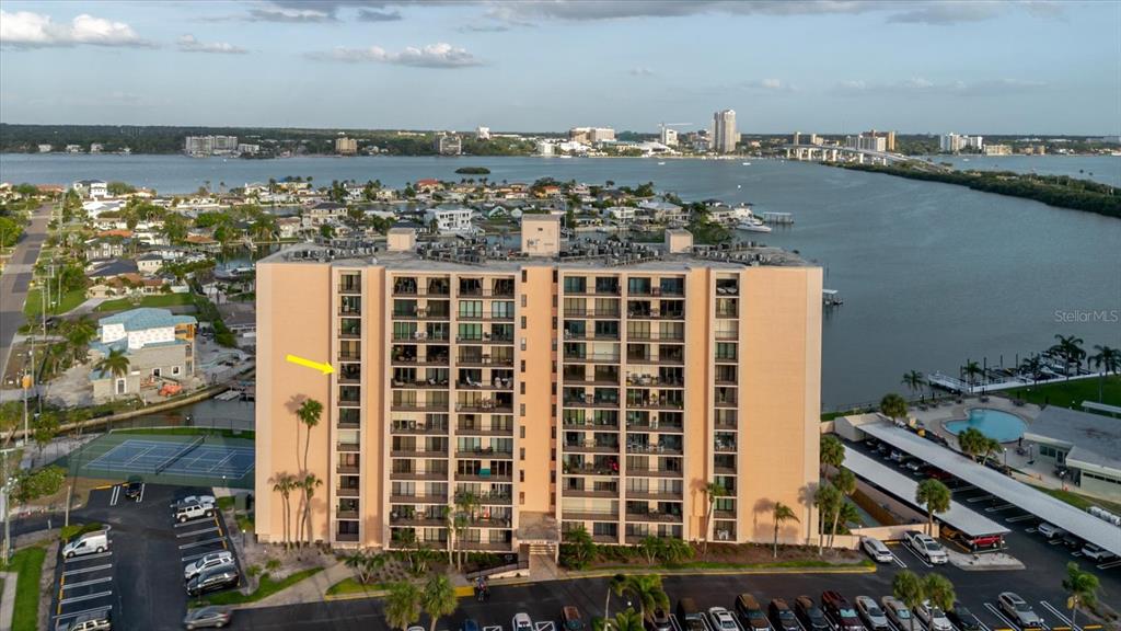 An aerial view shows a multi-story apartment building with a yellow arrow pointing to a balcony — 51 ISLAND WAY UNIT 801, CLEARWATER BEACH, FL