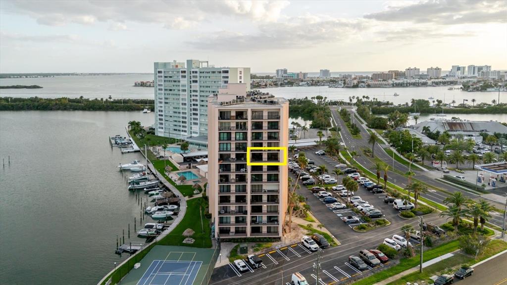 An aerial view shows a waterfront high-rise apartment building with a highlighted balcony unit — 51 ISLAND WAY UNIT 801, CLEARWATER BEACH, FL
