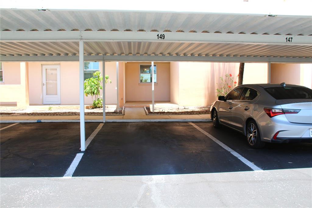 A covered parking space with a silver sedan parked under a carport structure — 7560 BAY ISLAND DRIVE S UNIT 149, SOUTH PASADENA, FL