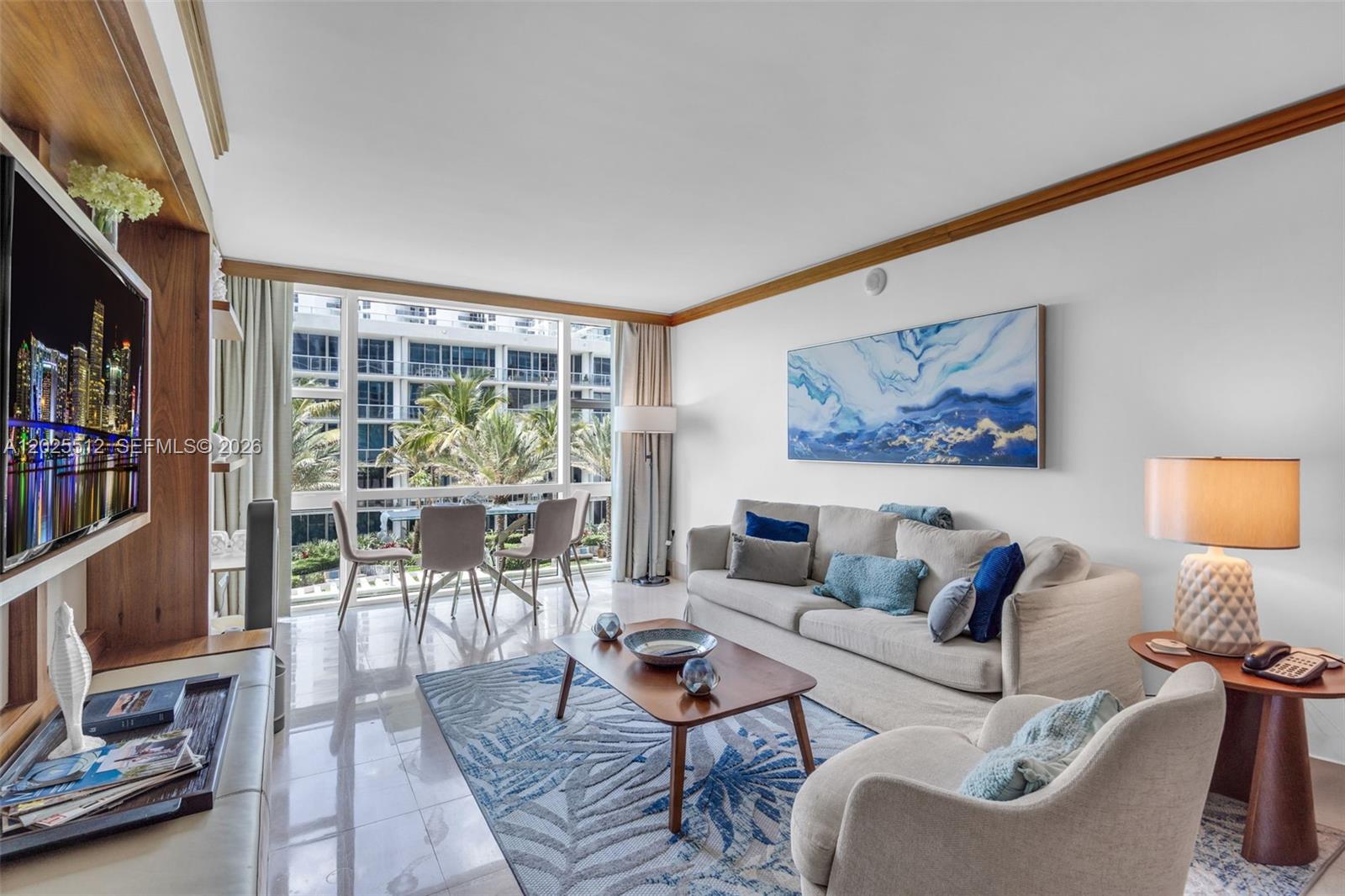 A living room features a sofa, armchairs, a coffee table, and a view of palm trees — 6801 Collins Ave, Miami Beach FL 33141, MIAMI BEACH, FL