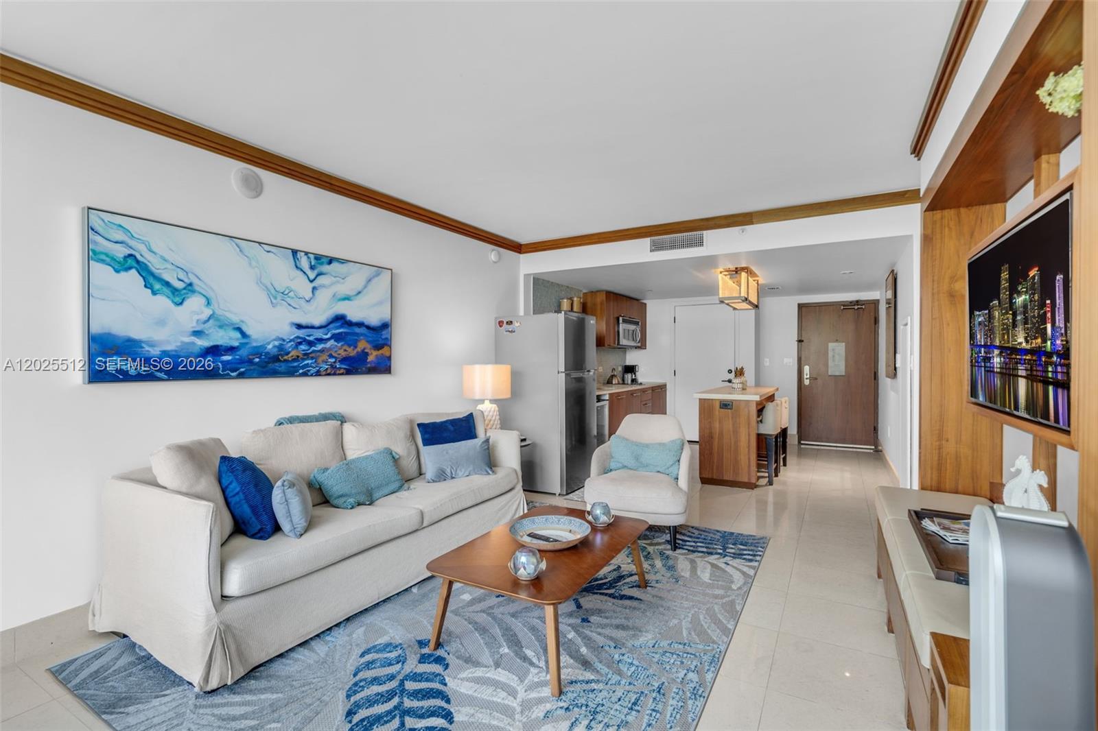 A living room features a beige sofa, a patterned rug, and an open kitchen area — 6801 Collins Ave, Miami Beach FL 33141, MIAMI BEACH, FL