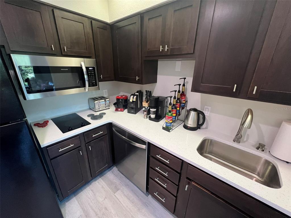 A kitchen features dark wood cabinets, stainless steel appliances, and white countertops — 8303 PALM PARKWAY UNIT 404, ORLANDO, FL