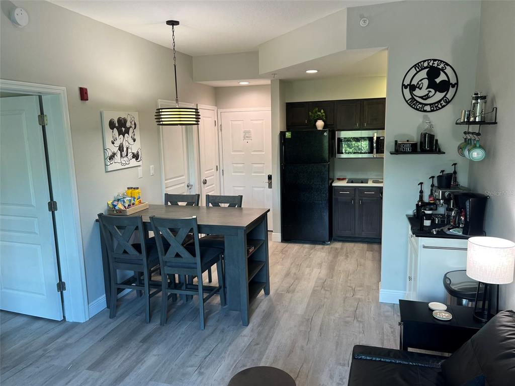 A kitchen and dining area features dark cabinetry, a black refrigerator, and a wooden table — 8303 PALM PARKWAY UNIT 404, ORLANDO, FL
