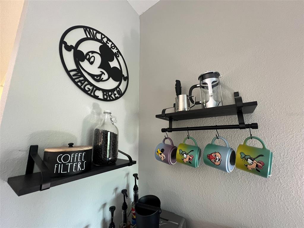 A coffee station features two black wall shelves, Disney-themed mugs, and a Mickey Mouse wall sign — 8303 PALM PARKWAY UNIT 404, ORLANDO, FL