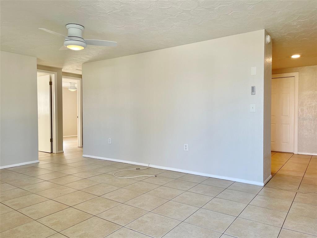 An interior view of a room with beige tile flooring, a ceiling fan, and light-colored walls — 5814 1ST AVENUE, NEW PORT RICHEY, FL