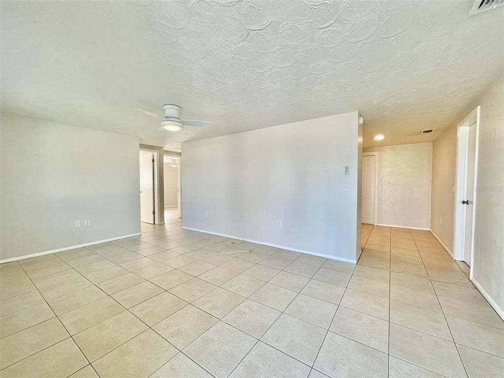 An empty room with light-colored tile flooring, a ceiling fan, and white walls — 5814 1ST AVENUE, NEW PORT RICHEY, FL