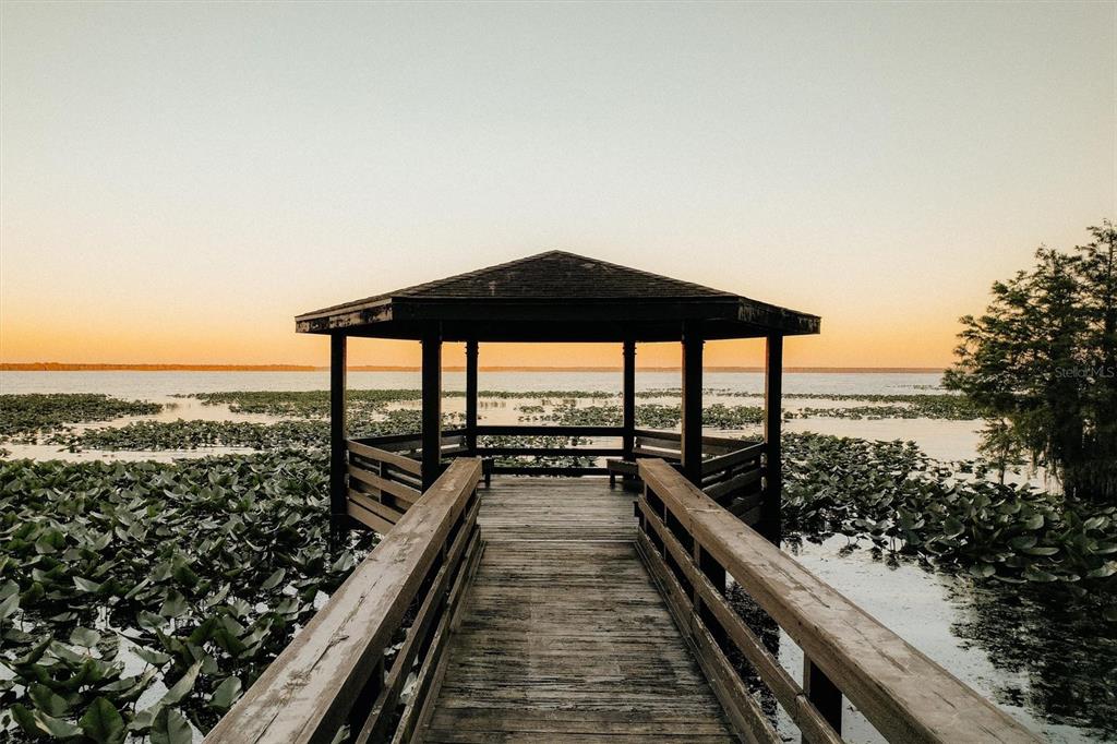 A wooden boardwalk leads to a gazebo situated over a lake filled with lily pads — 14023 SE 204TH TERRACE, HAWTHORNE, FL