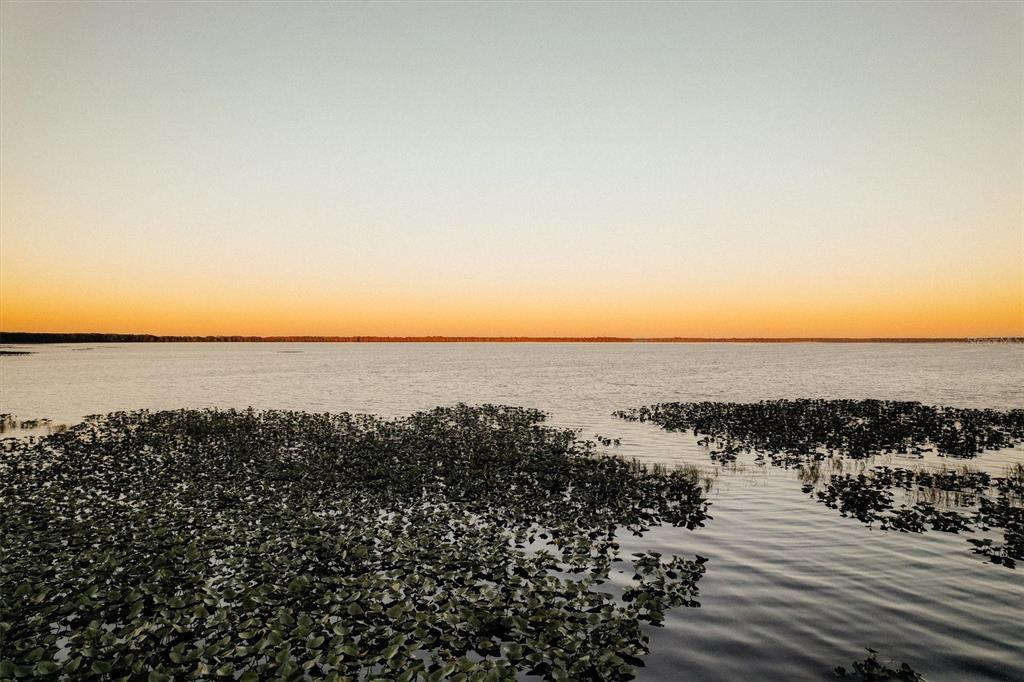A wide view of a calm lake at sunset with lily pads in the foreground — 14023 SE 204TH TERRACE, HAWTHORNE, FL