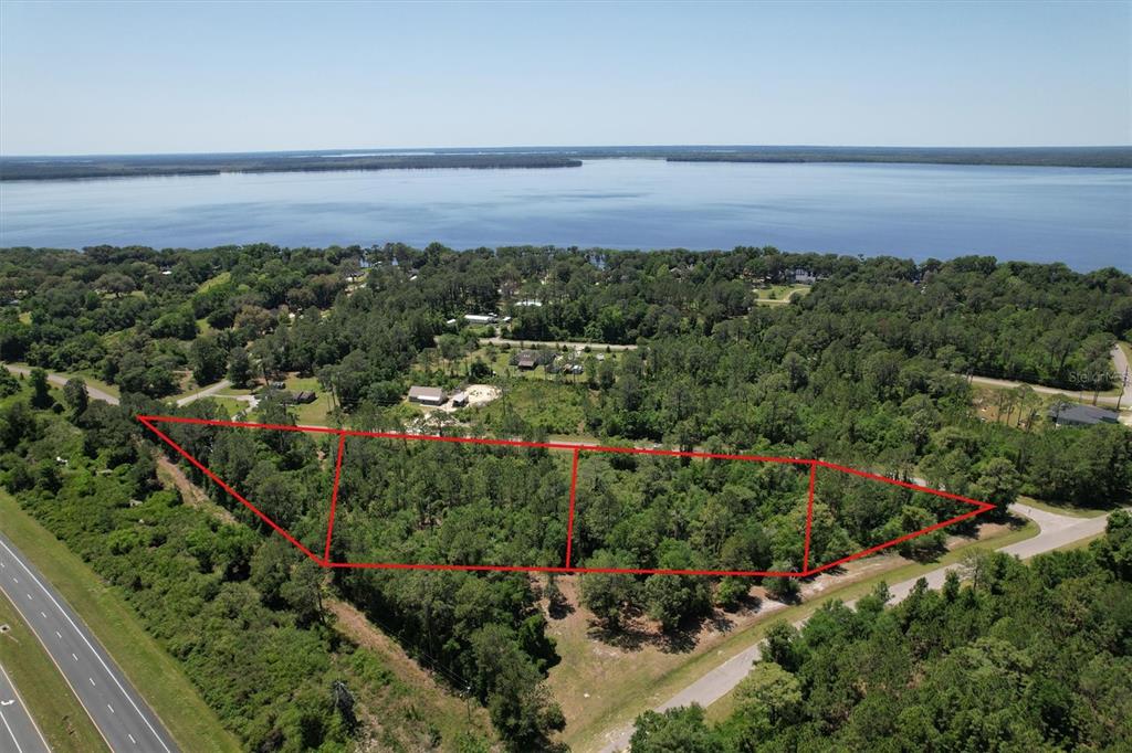 An aerial view shows two adjacent wooded lots outlined in red near a large lake — 14023 SE 204TH TERRACE, HAWTHORNE, FL