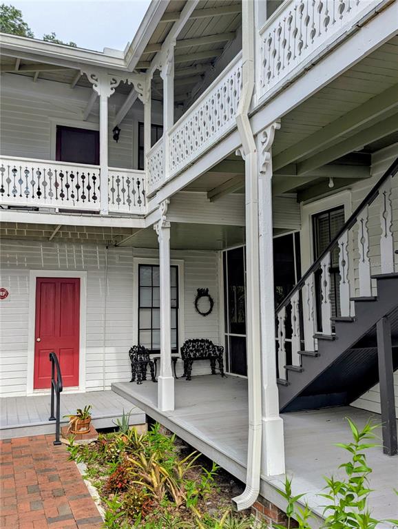 A two-story white wooden building features a covered porch, ornate railings, and a red door — 6635 SE 221ST STREET UNIT 2, HAWTHORNE, FL