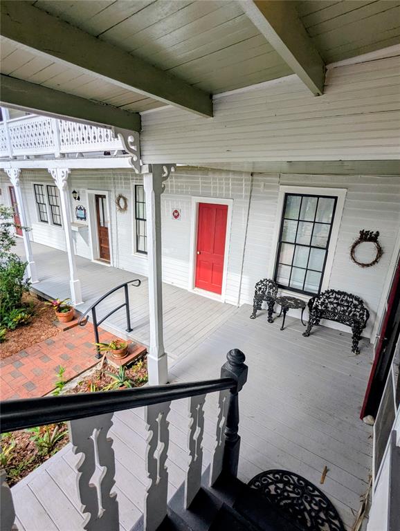 A wooden porch features a red door, black metal furniture, and white railings — 6635 SE 221ST STREET UNIT 2, HAWTHORNE, FL