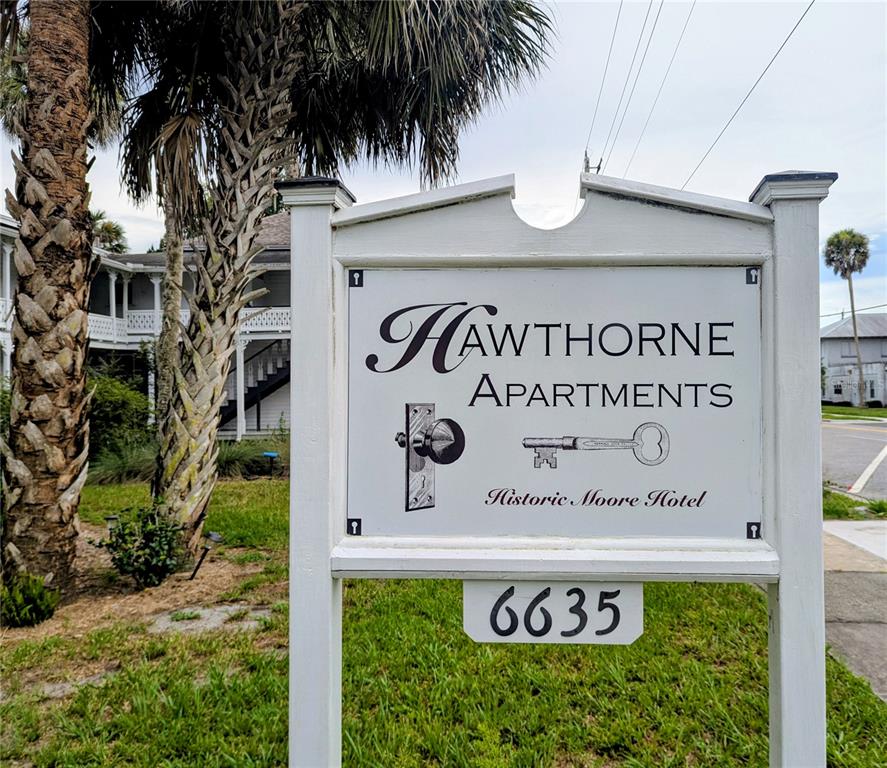 A white sign for Hawthorne Apartments stands in front of a historic building and palm trees — 6635 SE 221ST STREET UNIT 2, HAWTHORNE, FL
