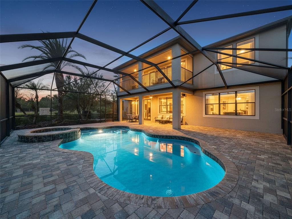 A two-story house with a screened-in pool and patio area at dusk — 10701 LAUREL VISTA WAY, TAMPA, FL