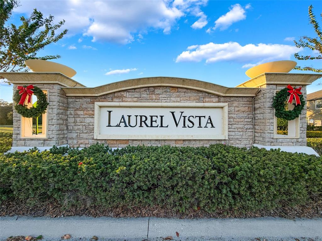 A stone monument sign for Laurel Vista features two wreaths and decorative lighting — 10701 LAUREL VISTA WAY, TAMPA, FL