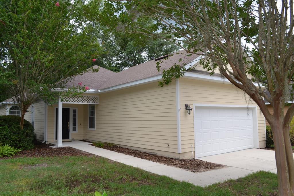 A single-story house with light yellow siding, a white garage door, and a front walkway — 79 NW 48TH BOULEVARD, GAINESVILLE, FL