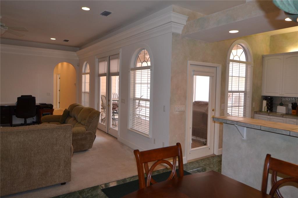 A living room and kitchen area with arched windows, crown molding, and tiled flooring — 79 NW 48TH BOULEVARD, GAINESVILLE, FL