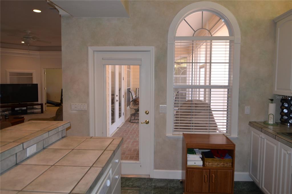 A kitchen features tile countertops, a glass-paneled door, and an arched window overlooking a patio — 79 NW 48TH BOULEVARD, GAINESVILLE, FL