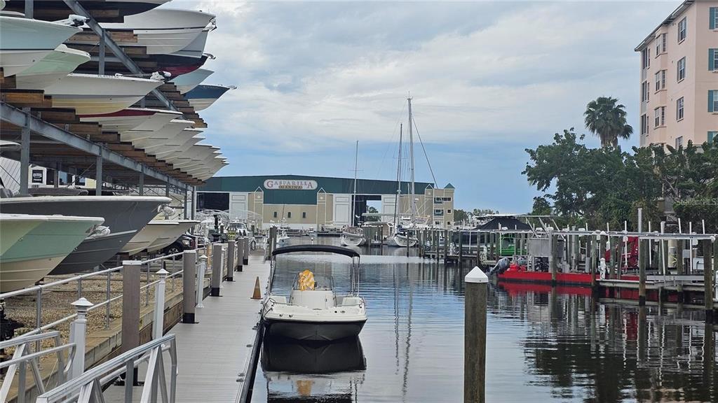 A marina features a boat storage rack, a central dock with a boat, and buildings — 12133 ASHLEY AVENUE, PORT CHARLOTTE, FL