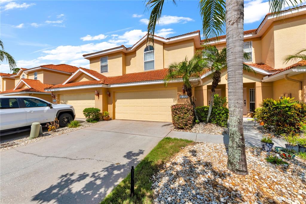 A two-story tan townhouse with a tile roof, a two-car garage, and a driveway — 1421 RIDGE TERRACE, TARPON SPRINGS, FL
