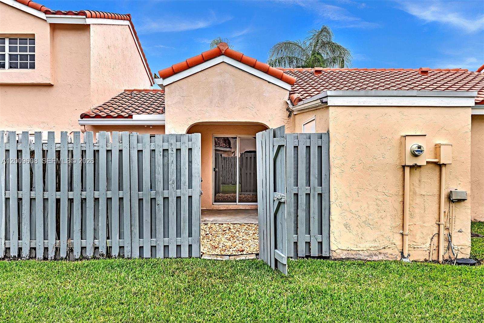A peach-colored house exterior features a gray wooden fence and a small gated patio — 1439 Springside Dr # 1439, Weston FL 33326, WESTON, FL