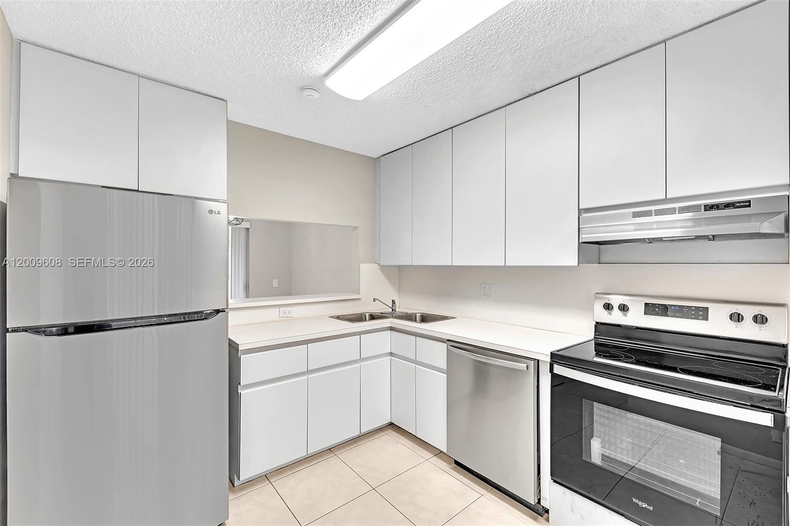 A kitchen features white cabinets, stainless steel appliances, and light-colored tile flooring — 1439 Springside Dr # 1439, Weston FL 33326, WESTON, FL