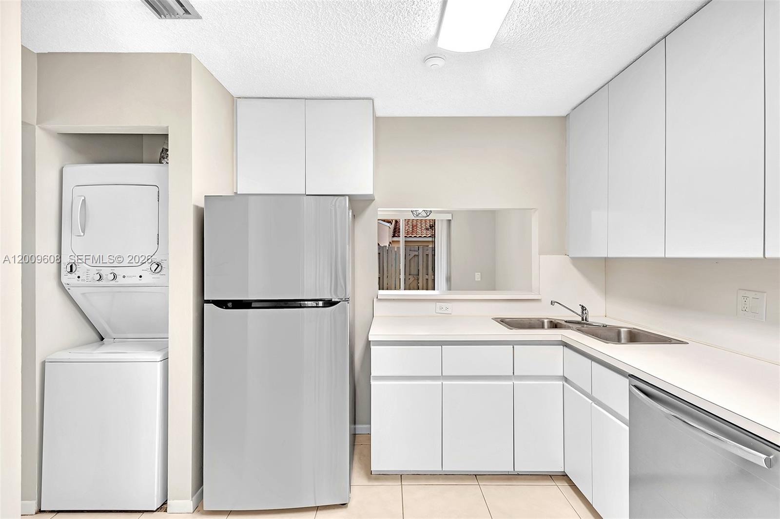 A kitchen features white cabinets, stainless steel appliances, a double sink, and a laundry closet — 1439 Springside Dr # 1439, Weston FL 33326, WESTON, FL