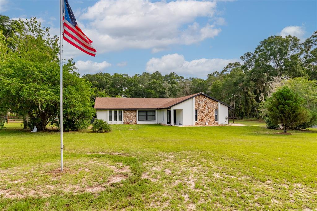 A single-story house with stone accents and a white exterior sits on a grassy lot — 2735 NE 127TH PLACE, ANTHONY, FL